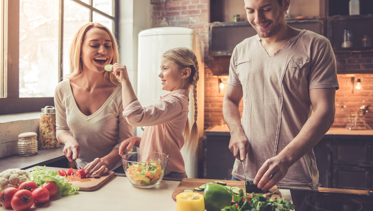 A happy family cooking together with fresh vegetable ingredients