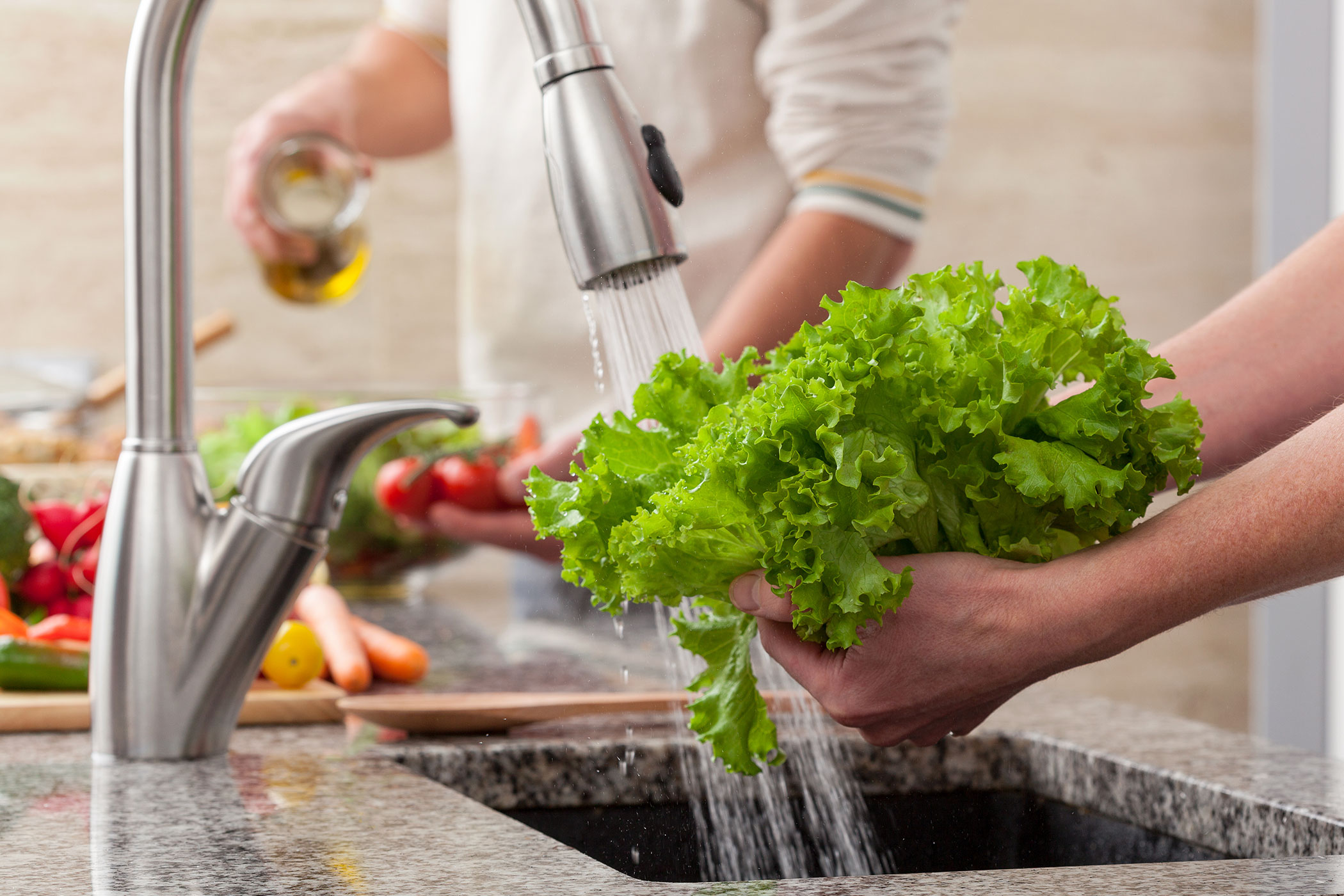 Person washing fresh vegetables from the tab over the sinl