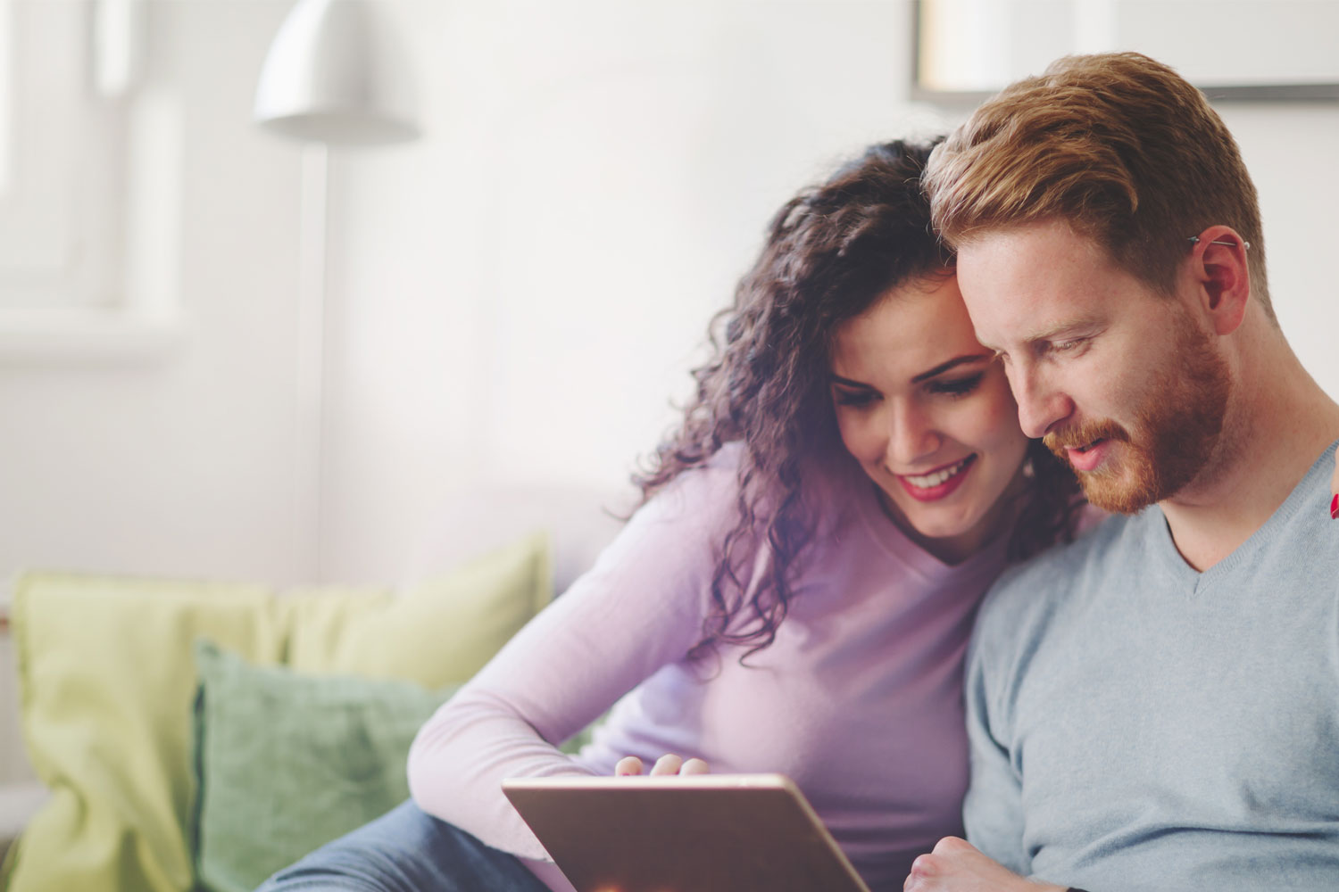 A couple in light pastel sweater looking the tablet together with satisfying face