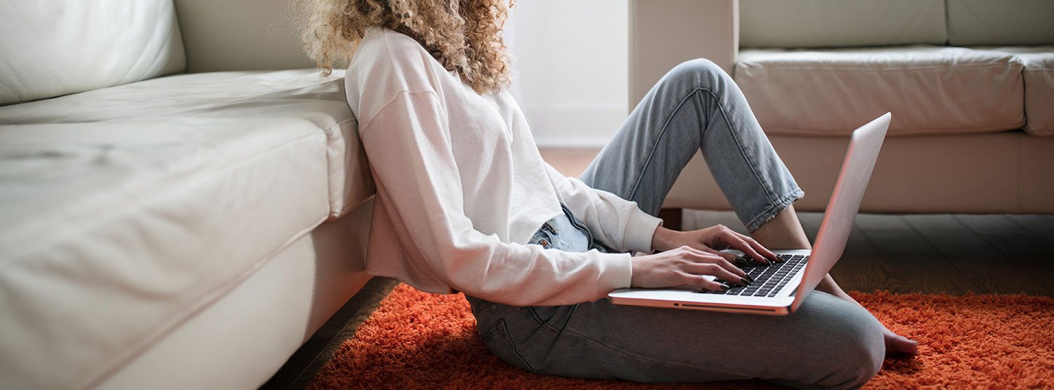 woman researching on laptop while she sits on the floor of her living room