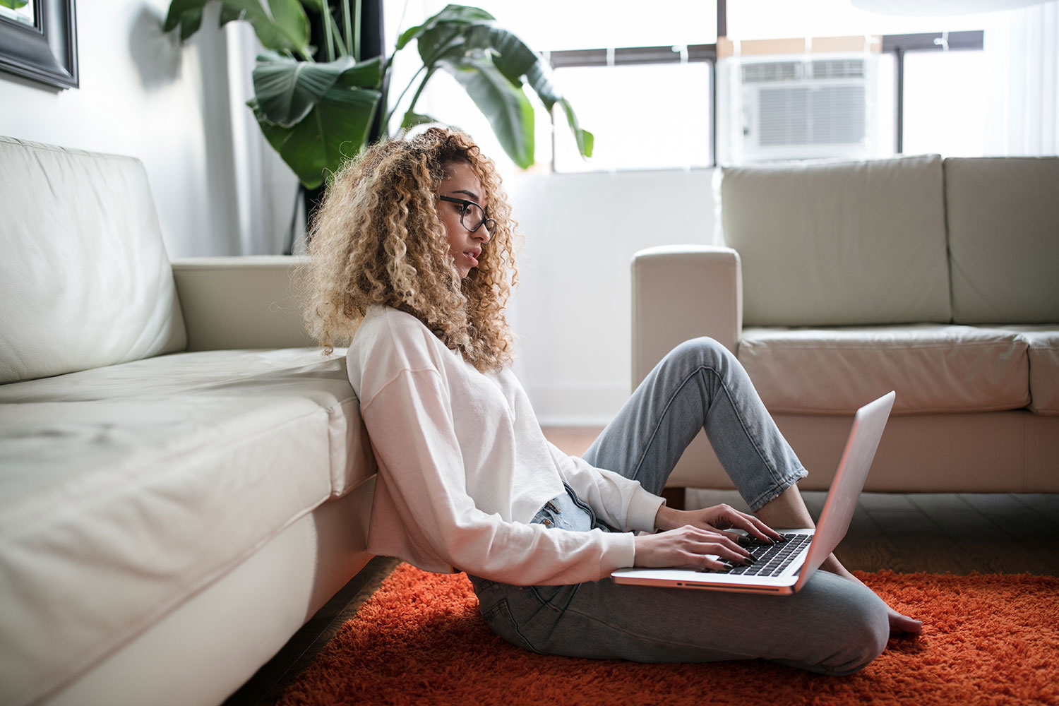 woman researching on laptop while she sits on the floor of her living room